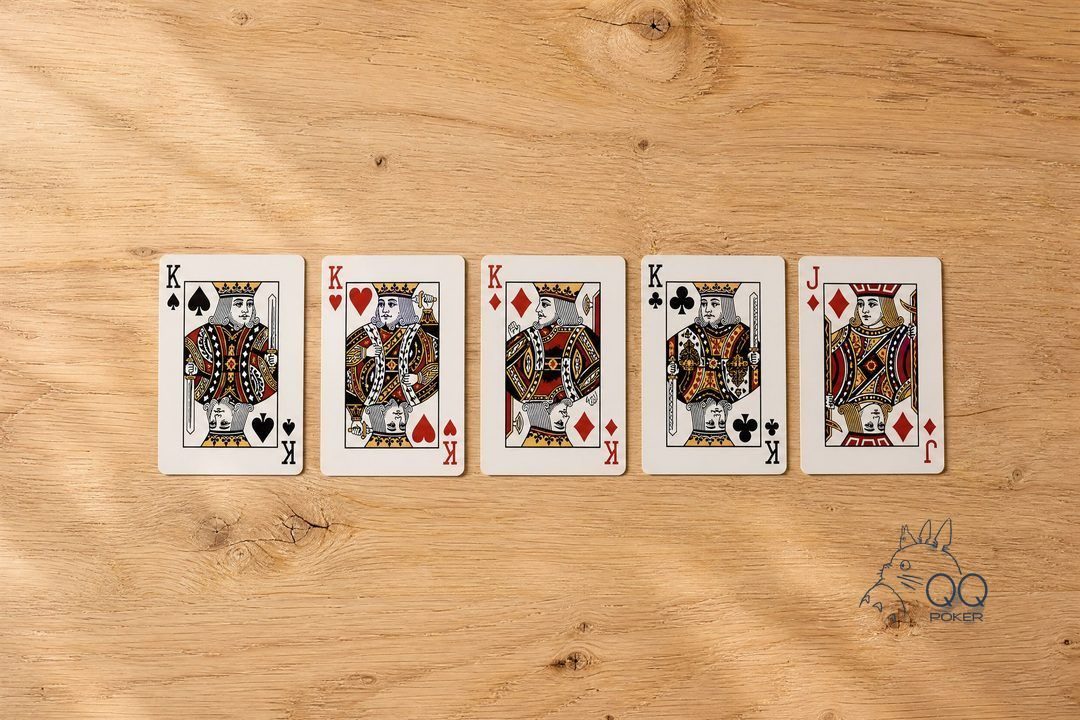 五张正面朝上的牌一字横排:黑桃 K、红桃 K、方块 K、梅花 K 带方块 J,四条,微俯